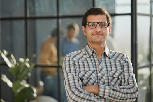 Handsome businessman standing with crossed arms and looking camera