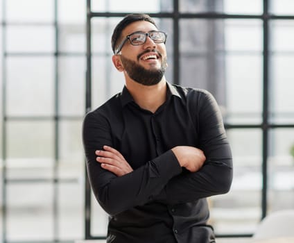 young businessman smiling in the office with his arms crossed