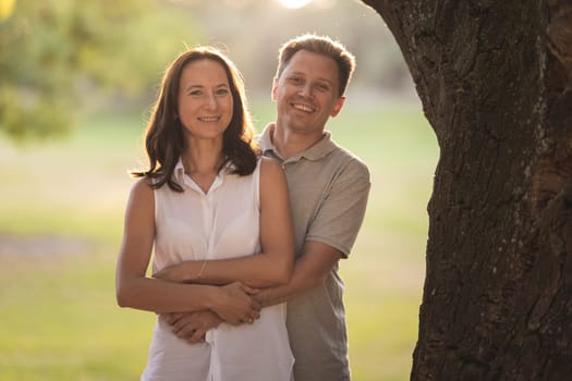 Adult white couple hugging on nature. Mid shot