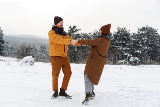 Young couple in love outdoor in snowy winter forest having a walk
