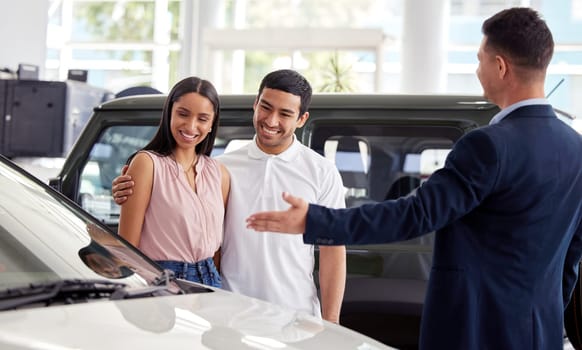 Couple at car dealership, choice and transportation with salesman, customer buying new transport with luxury. Sales, agreement and show cars with people at automobile showroom with purchase decision.