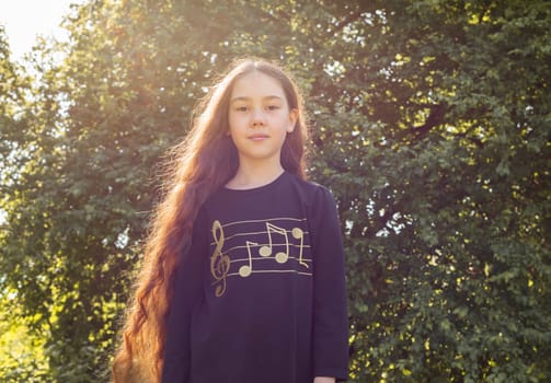 Portrait Adorable Girl With Long Shiny Smooth Hair Under Sun Halo Posing in Meadow. Caucasian Asian Brown Haired Child Enjoying Nature. Carefree, Happy Childhood, Hair Growth. Horizontal Plane