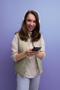 pretty young brunette woman listening to music using headphones and mobile phone.