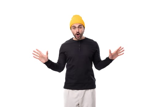 young surprised brutal male model dressed in a black jacket and yellow cap.