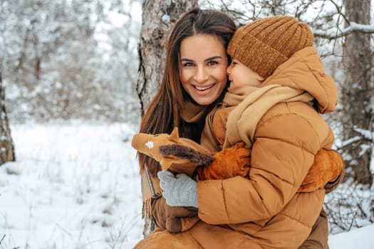 Woman with a little son on a winter hike in the snowy forest together