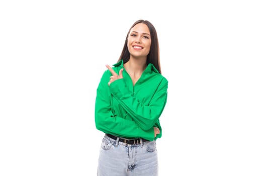 brown-eyed brunette young business lady in a green shirt shows her hand to the side on a white background with copy space.