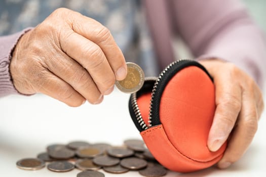 Asian senior woman holding counting coin money in purse. Poverty, saving problem in retirement.