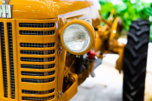 Small yellow tractor in an exhibition, closeup details, wheels