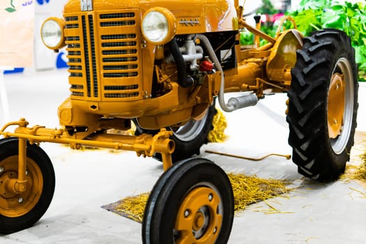 Small yellow tractor in an exhibition, closeup details, wheels