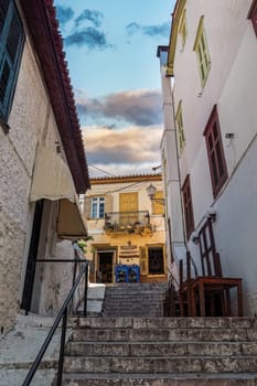 A staircase around buildings leading to a traditional store on a house with a balcony in Nafplion, Greece.
