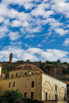 Nafplio, Vouleftikon, First Parliament of Greece stone-built exterior against Acronauplia fortress background with a blue sky with clouds.