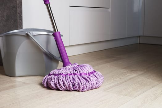 Purple mop on the bathroom floor. The concept of indoor cleaning. copy space.