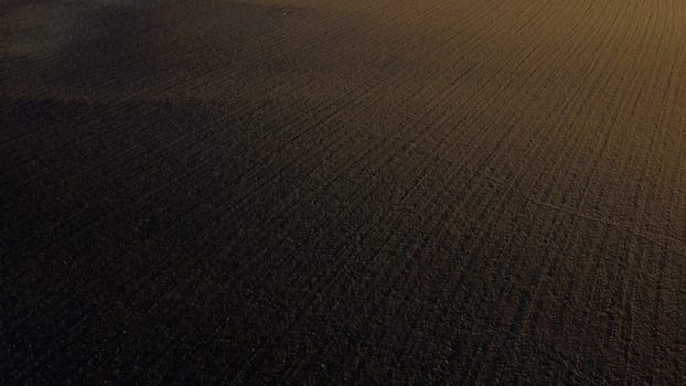 Landscape of plowed up land on an agricultural field on a sunny autumn day. Flying over the plowed earth with black soil. Agrarian background. Black soil. Ground earth dirt priming aerial drone view.