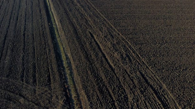 Landscape of plowed up land on agricultural field on sunny autumn day. Flying over plowed earth with black soil. Black soil. Ground earth dirt priming aerial drone view. Agrarian background. Uplift