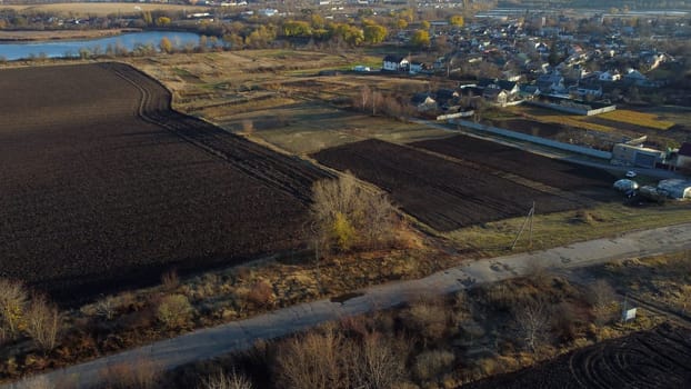 Beautiful rural country landscape houses, agricultural plowed fields, lakes ponds for growing fish, gardens, horticulture, home, village, city on sunny autumn day. Aerial drone view. Agrarian scenery