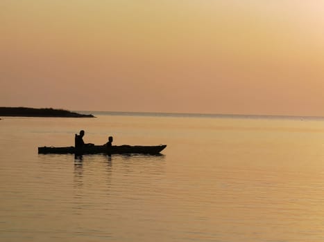 silhouette of a couple on a boat in the sea at sunset.