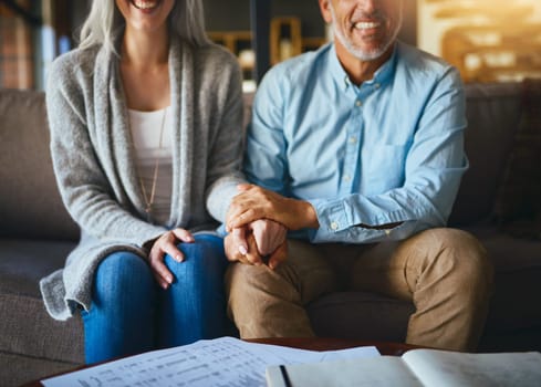 Holding hands, happy senior couple and life insurance support with paperwork in a living room. Home, sofa and elderly people with empathy, hope and trust with solidarity for investment in a lounge.