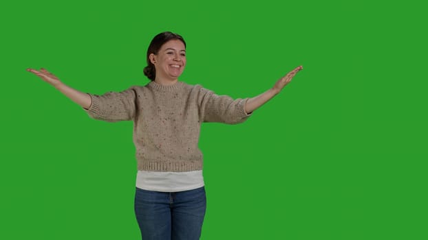 Front view of woman blowing kisses in studio to show love, expressing romantic feelings and optimistic emotions. Young adult acting confident and cheerful, being friendly on studio backdrop.