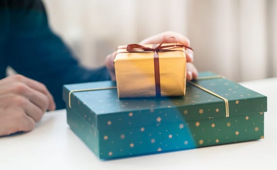 Male hands hold gifts in beautiful wrapping paper closeup view, a man prepares gifts for his loved one, relatives, friends and family for celebration the holiday.