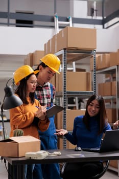 Storehouse employees getting inventory instruction from operator and taking notes. Shipment manager explaining logistics and distribution supply chain to industrial warehouse workers