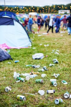 The product of some heavy partying. a campsite filled with litter with people in the background