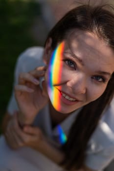 Portrait of caucasian woman with rainbow beam on her face outdoors