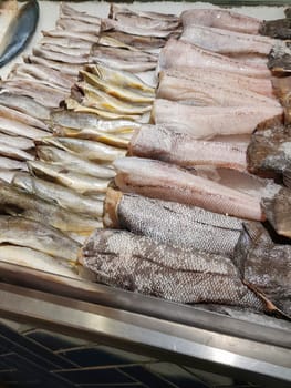 Food background close-up. There are many varieties of fresh fish on the ice lying in a row. Sale of fresh frozen fish at the fish market.