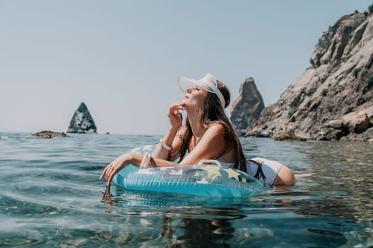 Woman summer sea. Happy woman swimming with inflatable donut on the beach in summer sunny day, surrounded by volcanic mountains. Summer vacation concept