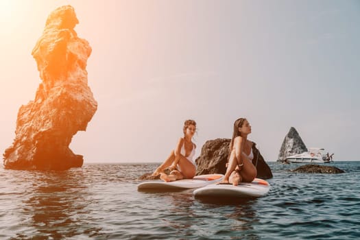 Woman sup yoga. Middle age sporty woman practising yoga pilates on paddle sup surfboard. Female stretching doing workout on sea water. Modern individual hipster outdoor summer sport activity