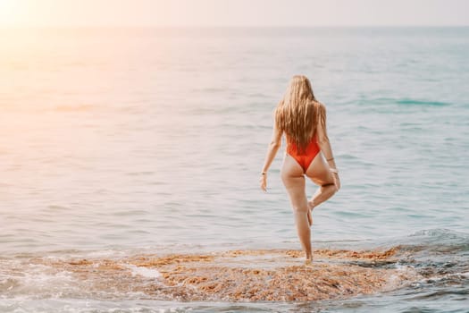 Woman sea yoga. Back view of free calm happy satisfied woman with long hair standing on top rock with yoga position against of sky by the sea. Healthy lifestyle outdoors in nature, fitness concept.