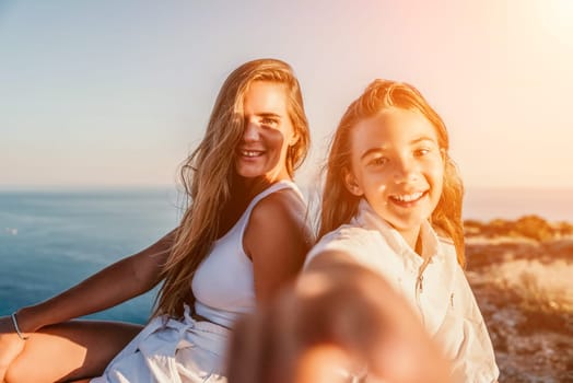 Close up portrait of mom and her teenage daughter hugging and smiling together over sunset sea view. Beautiful woman relaxing with her child.