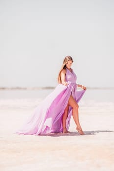 Woman pink salt lake. Against the backdrop of a pink salt lake, a woman in a long pink dress takes a leisurely stroll along the white, salty shore, capturing a wanderlust moment