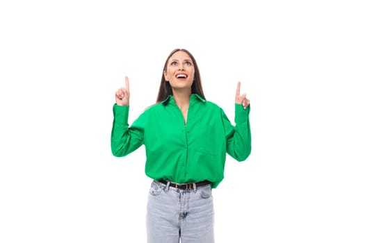 pretty young brown-haired female model with brown eyes in a green shirt points with her hands at the advertisement.