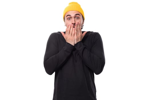 portrait of a surprised young 30s authentic brunet male adult in a black sweater on a white background with copy space.