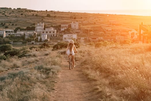 Woman travel bike. Happy woman cyclist sitting on her bike, enjoying the beautiful mountain and sea landscape, signifying the idea of an adventurous bike ride