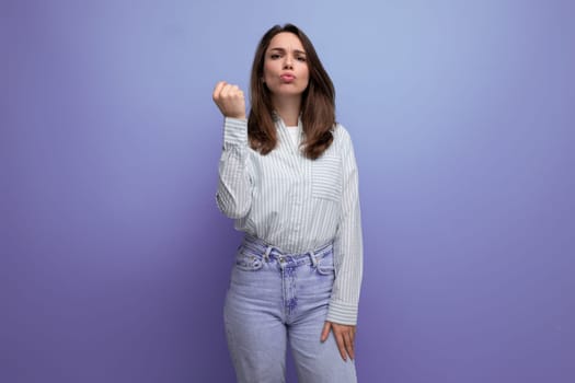 energetic emotional young brunette female adult in a striped shirt and jeans on a studio background.