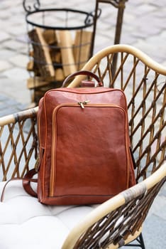 photo of a orange leather backpack with antique and retro look. rustic armchair