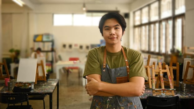 Portrait of asian man artist smiling confident, standing with arms crossed in art studio. Art, creativity, hobby, activity concept.