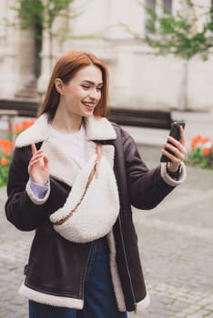 happy woman communicates with friends via video link outdoors on an old town street.