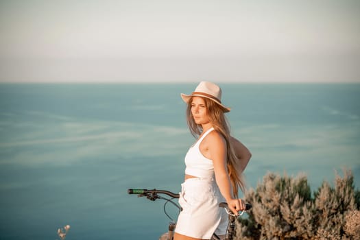 A woman cyclist on a mountain bike looking at the landscape sea. Adventure travel on bike