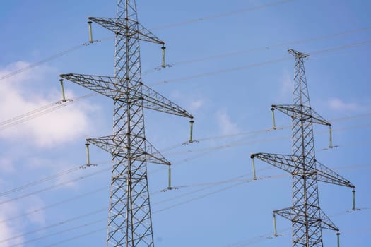 High voltage towers with sky background. Power line support with wires for electricity transmission. High voltage grid tower with wire cable at distribution station. Energy industry, energy saving.