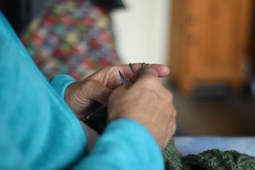Closeup of woman hands knitting with green yarn