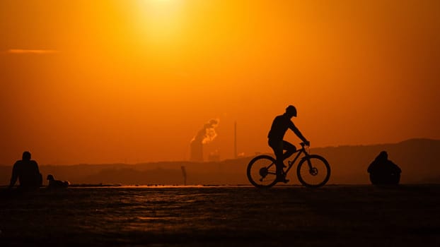 Silhouette shot of a man biking on a pathway during a golden sundown