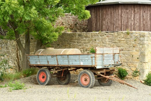 Agricultural trailer with slurry tank stands in front of old farm wall