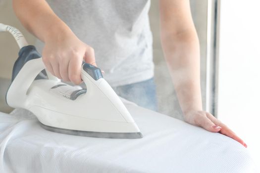 Close up of Female hands ironing white shirt on ironing board