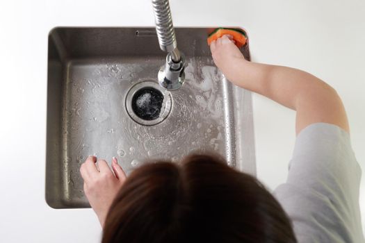 Woman cleaning sink with sponge and soap, top view