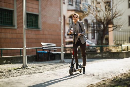 A young businesswoman with an electric scooter going to work through the city.