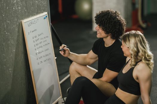 An attractive woman talking about exercise plan with her personal trainer at the gym.