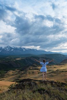 Woman in blue dress in summer Altai mountains in Kurai steppe