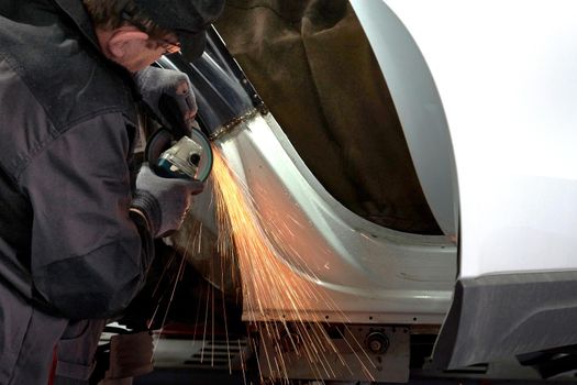Cutting metal part with sparks in car service station